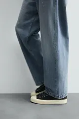 Pantalón de jean gris oscuro, corte amplio, con cinco bolsillos, efecto lavado y cierre frontal con cremallera y botón.