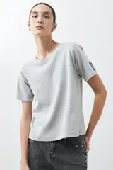Remera de manga corta color gris claro con logo pequeño en la manga.