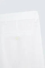 Pantalón de vestir blanco, confeccionado en lino, de corte recto, con bolsillos laterales y traseros. Se ajusta a la cintura con botón y cierre.