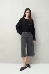 Sweater negro calado con diseño de líneas diagonales en relieve y mangas acampanadas.