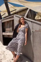 Vestido corto con estampado a cuadros blanco y negro, espalda descubierta con tiras cruzadas y falda acampanada.