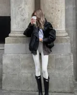 Chaqueta de efecto piel negra, con cuello alto estructurado y cierre asimétrico. Presenta un corte relajado y hombros ligeramente marcados.