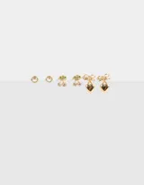 Set de tres pares de aros pasantes dorados: un par de aros con forma de cerezas con strass, un par de aros con forma de corazón con moño y un par de aros redondos con strass.
