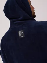 Poncho con capucha confeccionado en tejido de toalla de algodón, color negro, con el logo de la marca Rusty bordado en blanco en el frente.