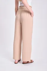 Pantalón color beige de corte ancho, con lazo ajustable en la cintura.