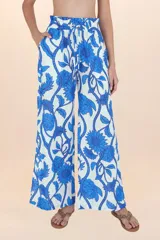 Pantalón palazzo blanco con estampado floral azul, cintura alta con elástico y cordón ajustable.