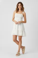 Vestido corto blanco de algodón con broderie, corte ancho, breteles finos con lazo y escote recto.