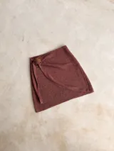 Falda corta cruzada de tejido de punto con detalle de hebilla de madera, en color burdeos.