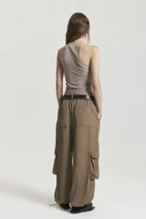 Pantalón cargo ancho color marrón, con cintura elástica y bolsillos cargo con tapa en la pierna. El bajo del pantalón se ajusta con cordón elástico.