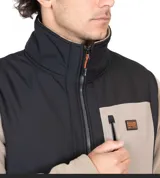 Campera micropolar color beige con bloques en negro y gris. Tiene cierre frontal completo, cuello alto, bolsillos laterales con cierre y logo de la marca bordado en el pecho.