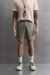 Shorts de entrenamiento color verde oliva, confeccionado en tejido técnico ligero y elástico con perforaciones. Tiene forro interior, cintura elástica ajustable con cordón, bolsillos laterales, bolsillo trasero con cierre de cremallera, bajo con aberturas laterales y logo estampado en la pierna.