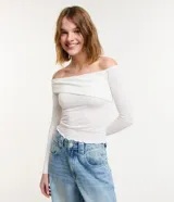 Blusa blanca texturizada con escote asimétrico hombro a hombro y mangas largas.