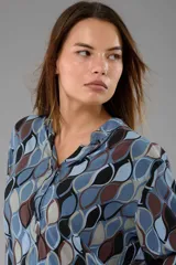 Camisa celeste con estampado de hojas en tonos marrón, gris y negro, con cuello mao y mangas largas.