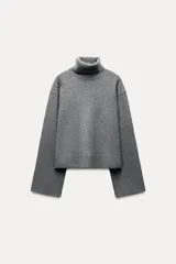 Sweater gris de lana con cuello alto, corte oversize y mangas largas acampanadas.