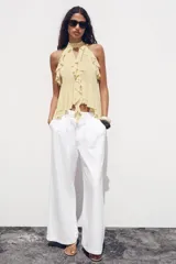Top color rosa viejo de cuello halter ajustable con lazadas. Detalle de abertura en el delantero y volantes en el mismo tejido.