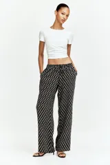 Pantalón recto de viscosa color negro con estampado de flores pequeñas en blanco. Tiene tiro bajo, elástico en la cintura y bolsillos al bies.