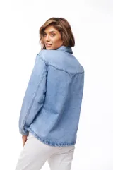 Sobrecamisa celeste de jean con cuello camisero, cierre frontal con botones dorados, dos bolsillos con solapa en el pecho y mangas largas con puños abotonados.