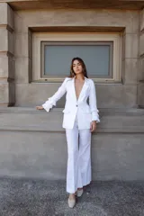 Pantalón de lino color beige, de tiro alto y pierna levemente acampanada, con pinzas delanteras.