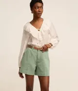 Short de mujer de sarga color beige claro, tiro alto, con pespuntes contrastantes en color blanco o crema. Presenta un corte regular y bolsillos delanteros y traseros.