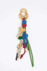 Llavero con mosquetón dorado y colgantes de cabos trenzados en colores rojo, azul y beige, junto con un dije dorado con forma de llave y detalles en verde.