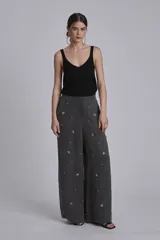 Pantalón palazzo gris con apliques de lentejuelas y mostacillas formando flores.