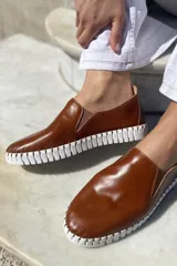 Slippers de cuero celeste con elásticos laterales y suela de goma blanca.