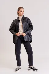Campera negra simil cuero con flecos en el frente, cuello clásico, cierre con botones a presión y corte holgado.