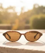 Gafas de sol con montura ovalada de color marrón chocolate y lentes polarizadas color marrón.