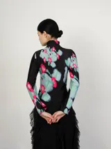 Polera de cuello alto y mangas largas, confeccionada en tela sublimada con estampado abstracto en tonos negro, azul, verde y rosa.