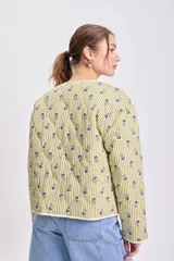 Chaqueta acolchada color verde claro con rayas verticales y pequeños estampados florales en tonos azules y verdes. Tiene cuello redondo, cierre frontal con botones y ribetes de color crudo.