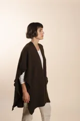 Ruana color crema tejida en punto fantasía con efecto de volado en los bordes.