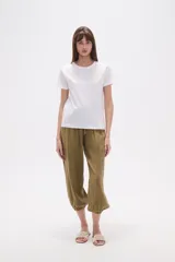 Remera blanca de algodón con cuello redondo y manga corta. Presenta un bordado lineal en tono claro, simulando formas orgánicas o florales, adornado con pequeñas mostacillas.