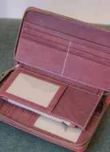 Billetera rectangular de cuero color naranja con cierre de cremallera y diseño geométrico en relieve.