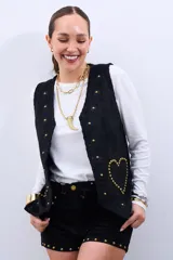 Chaleco negro con apliques de flores y tachas doradas en forma de corazón.