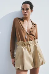Chaqueta marrón de punto liso con cuello polo y manga larga. Cierre frontal con botones.