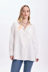 Camisa blanca de lino de manga larga con cuello clásico, cierre frontal con botones y bolsillo en el pecho.