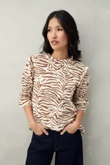 Blusa color beige con estampado abstracto en blanco, corte relajado, mangas 3/4 fruncidas y cuello con volados.