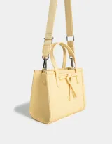 Cartera mini city color amarillo claro, de cuerina trenzada, con doble asa corta de mano, correa regulable desmontable, cierre superior y moño decorativo.