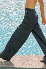 Pantalón ancho azul de tiro alto confeccionado en lino, con bolsillos delanteros con falsos botones y cierre lateral con cremallera oculta.