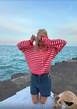 Buzo tejido a rayas horizontales rojas y blancas, con cuello tipo camisa y abotonadura frontal.