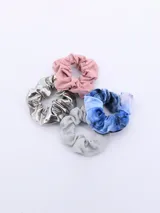 Pack de cuatro coleros de pelo con diseños variados: uno rosa liso, uno plateado brillante, uno azul con efecto tie-dye y uno plateado con glitter.