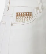 Bermuda mom de cintura mediana color blanco, confeccionada en sarga con detalle de bordado en el bolsillo reloj. Presenta trabillas en la cintura, cierre tradicional, bolsillos y costura contrastante aparente.