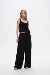 Pantalón negro de viscosa, corte ancho y tiro alto, con elástico en la cintura y bolsillos laterales.