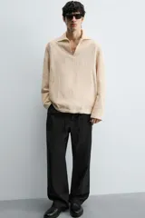 Pantalón negro de corte relajado y pierna ancha, confeccionado en mezcla de algodón y lino. Presenta cintura elástica ajustable con cordón y cierre frontal con cremallera y botón.