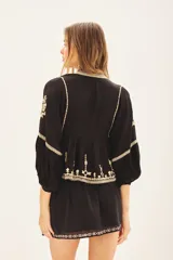 Blusa negra de viscosa crepe con escote en V, mangas largas con terminaciones elásticas y bordado de hilo color crema.