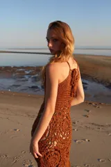 Vestido largo de crochet color marrón con diseño calado y flecos en el ruedo. Tejido a mano con hilos de lurex.