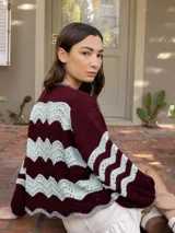 Campera tejida color borgoña con diseño de ondas en color celeste y detalles calados.