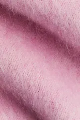 Buzo de punto rosa claro, con textura suave y peluda, cuello redondo y mangas largas de corte caído.