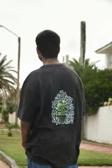 Remera blanca de algodón con cuello redondo y mangas cortas. Estampado en la espalda con un jarrón con flores y la palabra 'tuya'.