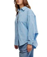 Camisa a rayas verticales color crema y marrón, de corte oversize y estilo masculino. Tiene cuello camisero, cierre frontal con botones y canesú en la espalda.